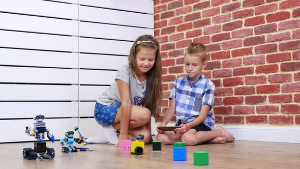Sevenyearold Boy and Girl Play Electronic Robots Cars Modern Toys on the Radio Control
