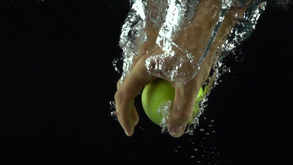 Man Hand Reaches And Grabs Green Apple Floating In Water