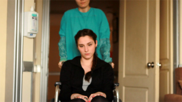 Nurse Carrying Patient in a Wheelchair at Hospital