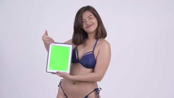 Happy Young Beautiful Asian Tourist Woman in Bikini Showing Digital Tablet