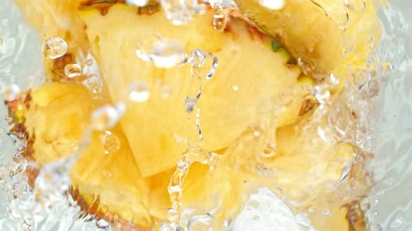 Super Slow Motion Shot of Pineapple Slices Falling Into Water Whirl at 1000 Fps