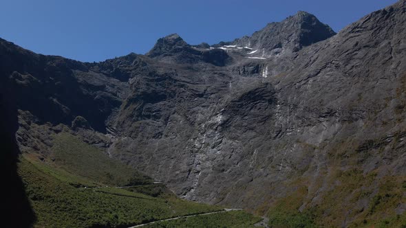 Waterfall on the steep slopes of tall mountain peak in Fiordland Southland, New Zealand. Aerial view