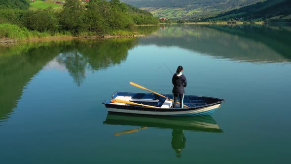 Woman on the Boat Catches a Fish on Spinning in Norway