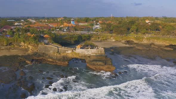 Famous Tanah Lot Temple on Sea in Bali Island, Indonesia with Blue Sky and Waves. Aerial View 