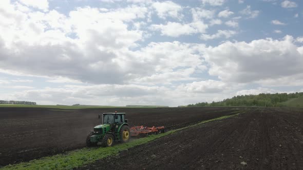 Tractor plows the ground with a plow in the field