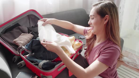 Cute woman folded clothes and packed a suitcase to happily prepare for a trip