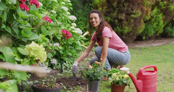 Happy biracial woman gardening, planting flowers