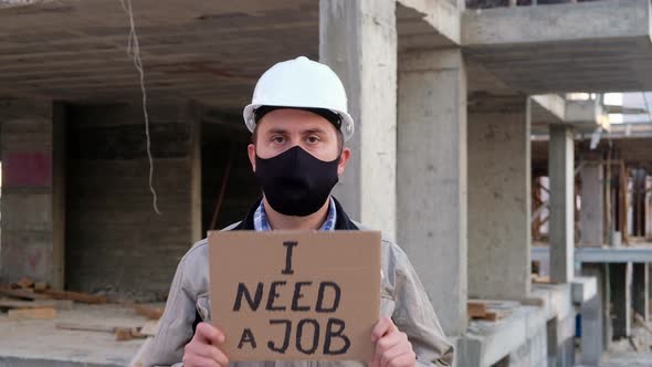 Engineer in Mask and Hardhat Shows Placard I Need a Job