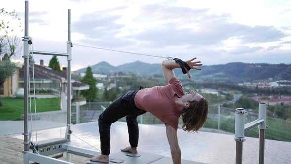 Man doing yoga in Wheel pose on pilates reformer