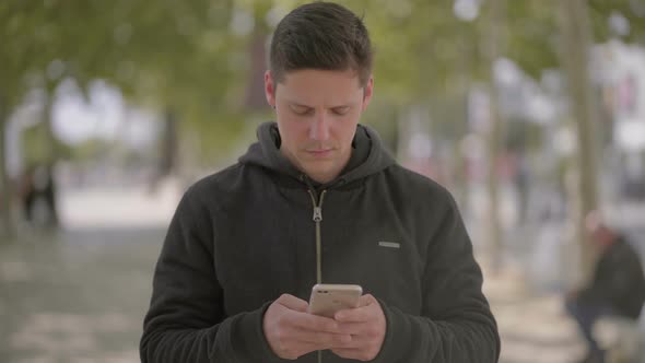 Focused Man Walking with Smartphone on Street