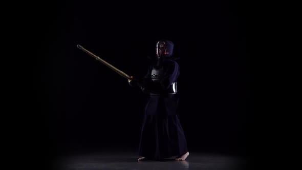 Masculine Kendo Warrior Practicing Martial Art with the Bamboo Bokken on Black Background. Slow