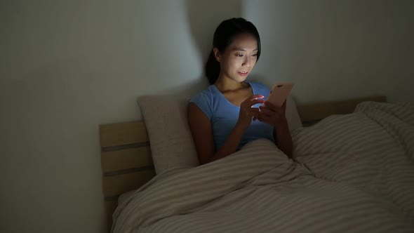 Woman using mobile phone before sleep at night