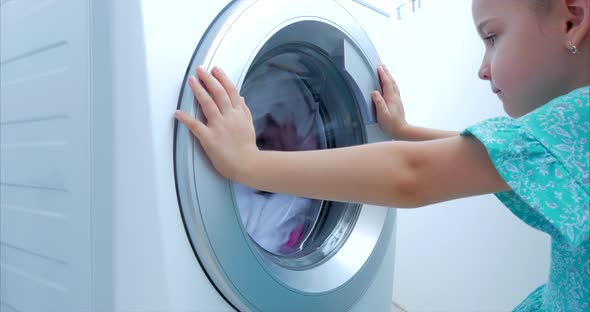 Cute Child Looks Inside the Washing Machine. Cylinder Spinning Machine. Concept Laundry Washing