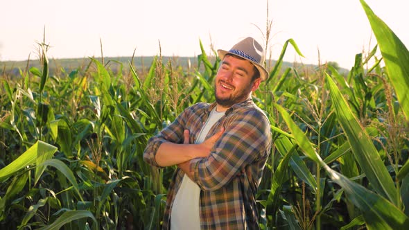 Young Man Farmer in Hat is Standing Pretty in Cornfield Turning Head and Smiling at Camera Front