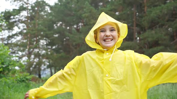 Happy Girl in Yellow Raincoat Walks on Ground Road in Forest
