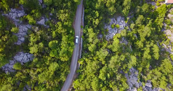 Aerial drone view of a minivan car vehicle driving on a rural road