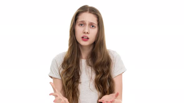 Indoor Portrait of Displeased Teenager Woman in Casual Tshirt Gesturing Hands in Irritating Manner