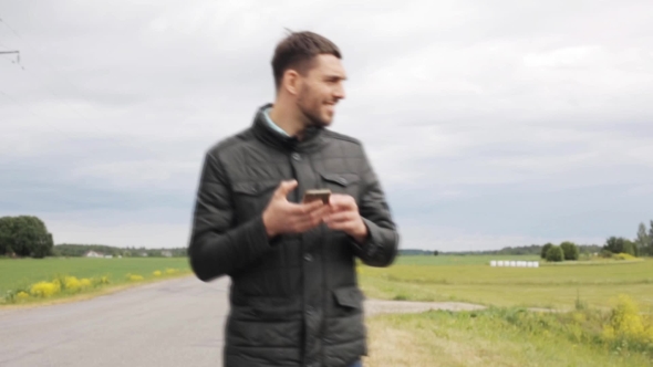 Man With Smartphone Walking On Countryside Road 16