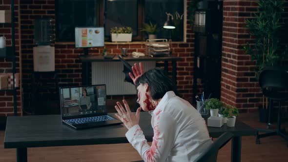 Angry Creepy Office Zombie Sitting at Desk While Gesturing Angrily at Digital Video Call