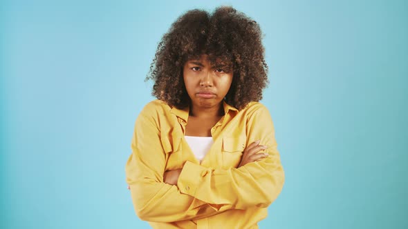 Africanamerican Lady Looking Sad and Offended Folding Hands on Chest While Posing Against Blue