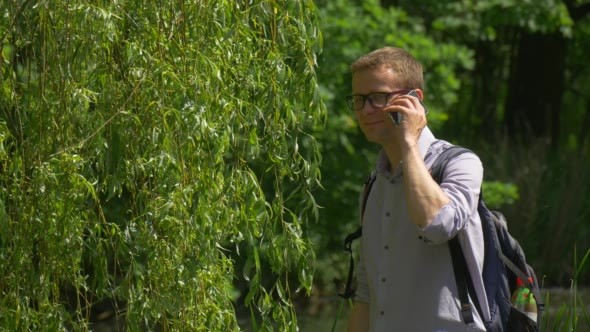 Man Makes Video Call in Park Waves His Hand