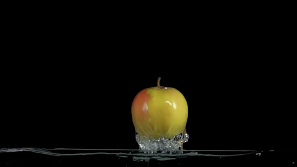 Green Apple is Bouncing From the Water with Splashes of on the Black Background