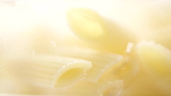 Boiling Water And Yellow Pasta In Glass Pan