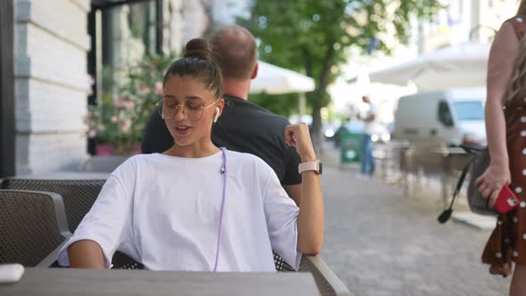 Beautiful Young Woman Sitting in Street Cafe