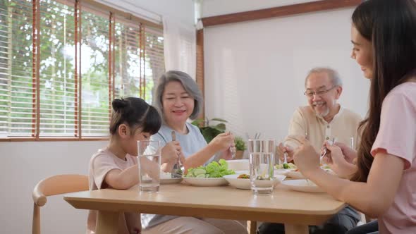 Happy family, Young little kid daughter enjoy eating food with father, mother and grandparents.