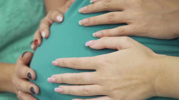 Side View of Four Female Caucasian Hands Caressing Belly of the Expectant Woman. Young Women Having