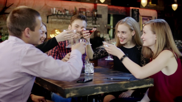 Company Of Young Friends Is Clinking Glasses In The Bar