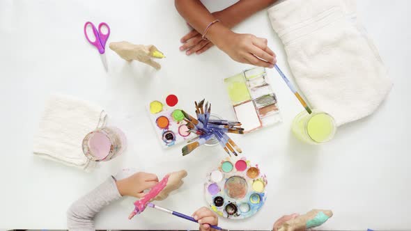 Step by step. Little girls painting paper mache unicorn with acrylic paint.