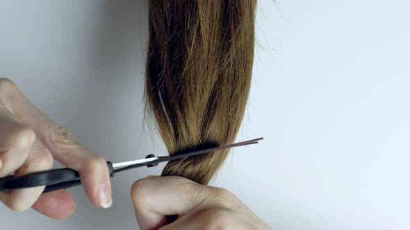 Upset Woman Cuts Her Long Straight Hair with Scissors