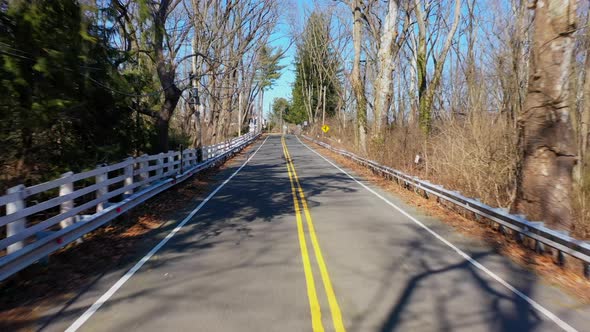 A low angle drone shot of an empty country road on a sunny day. The camera dolly out, then tilt down