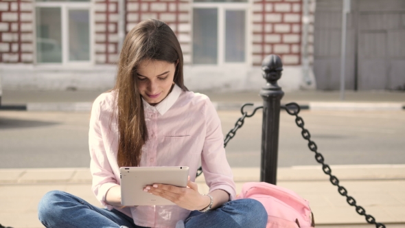 Young Beautiful Student Girl Using a Tablet Computer Outside. 