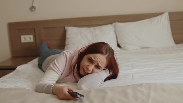 Young Woman in Casual Clothes Lying on Bed and Watching Tv