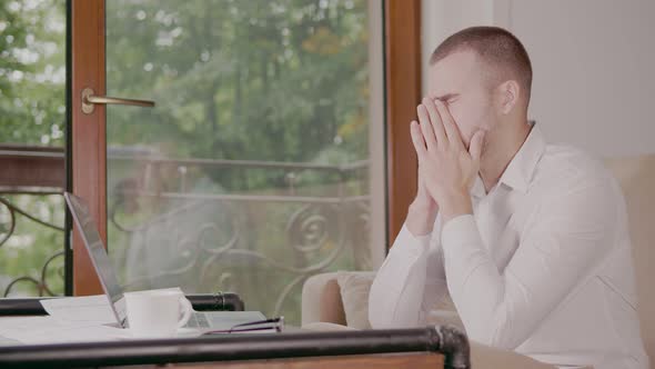 Businessman Despairing While Sitting at Laptop