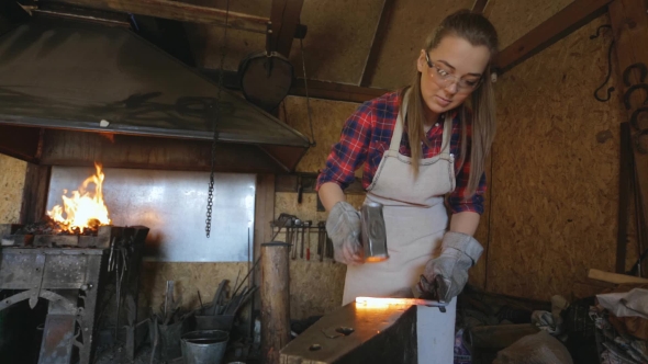 Woman Blacksmith Strikes Hammer On Hot Metal Workpiece.