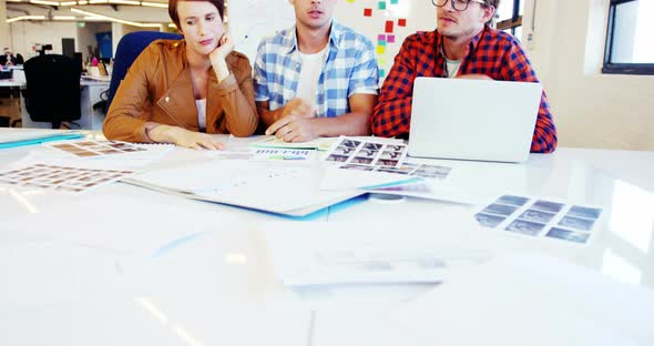 Graphic designer holding photo sample and interacting with colleagues