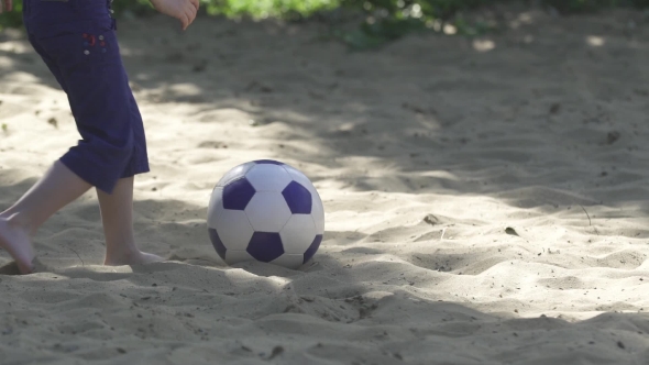 Legs Of The Boy Kick a Football''s Ball At Sand