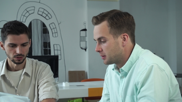 Two Young Professional Men Working Together At The Modern Office