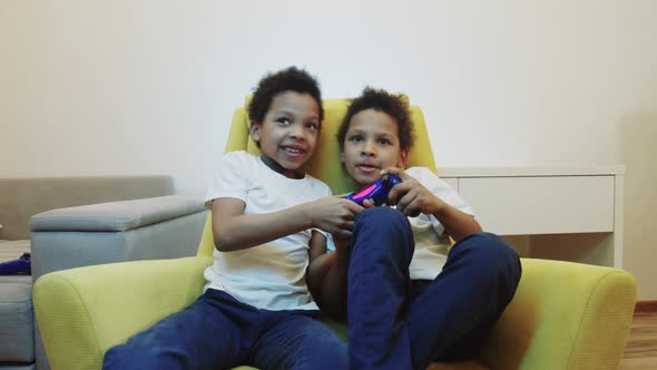 Two Little Black Boys Brothers Playing a Game and Fighting for a Joystick