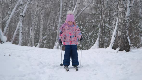 Little Girl Skiing in Winter Snowy Forest