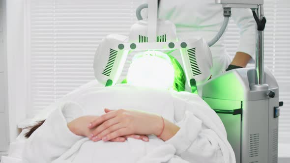 Electric Face Cleaning  a Glowing Green Device Over the Face of a Young Woman  Cosmetology