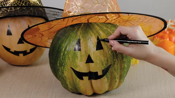 Teenage Girl Drawing Scary and Funny Jack O Lantern Face on Pumpkin with Black Marker Pen for