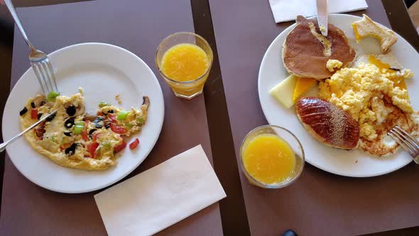 Time Lapse People Eating with Knives and Forks From Full Plates and Drinking Orange Juice