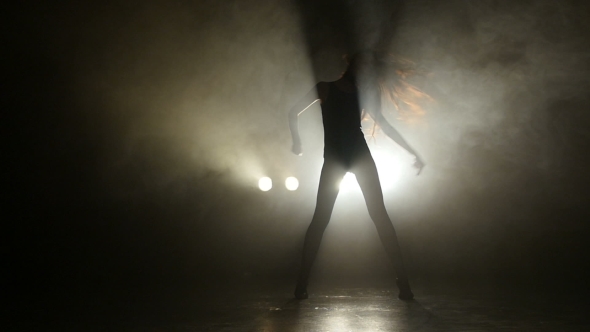 Silhouette Of a Girl Dancing On The Background Lights. 