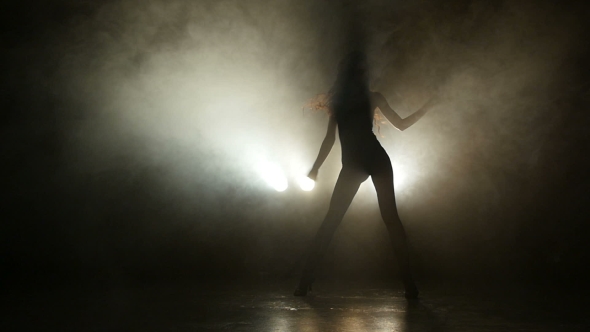 Silhouette Of a Girl Dancing On The Background Lights. 