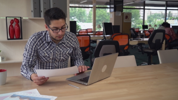 Man Working With Financial Diagrams In Empty Startup Office.