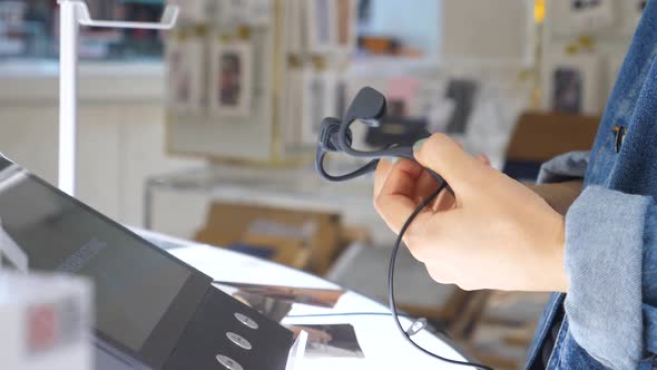 Female Customer Choosing Wireless Earphones In Store